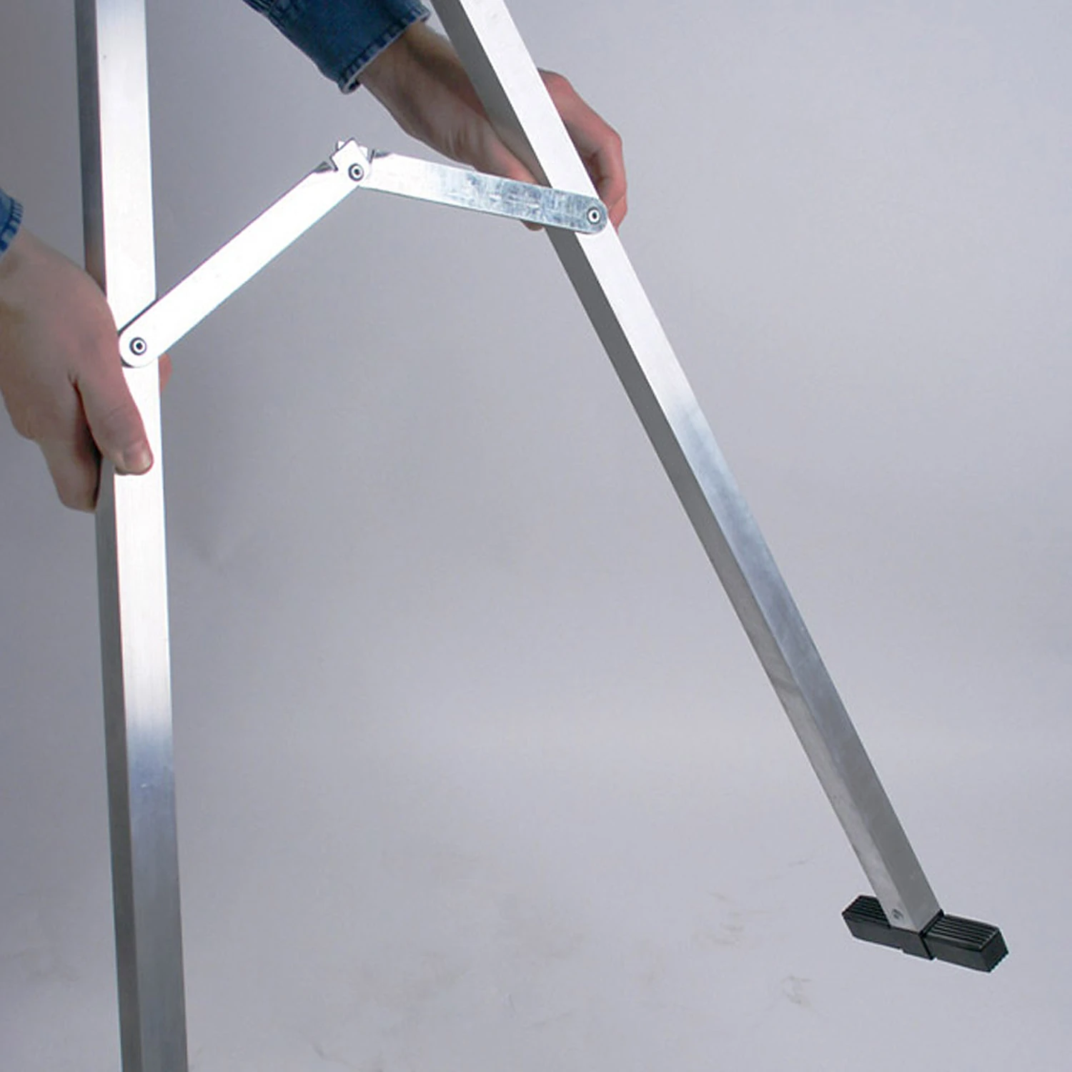 Unfolding the hinged spreader brace between the frame legs