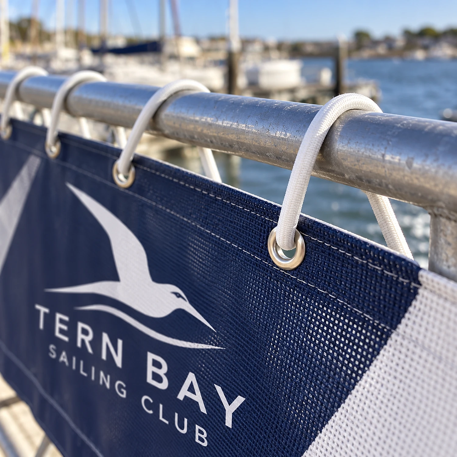 White bungee cord lacing a mesh banner to a railing