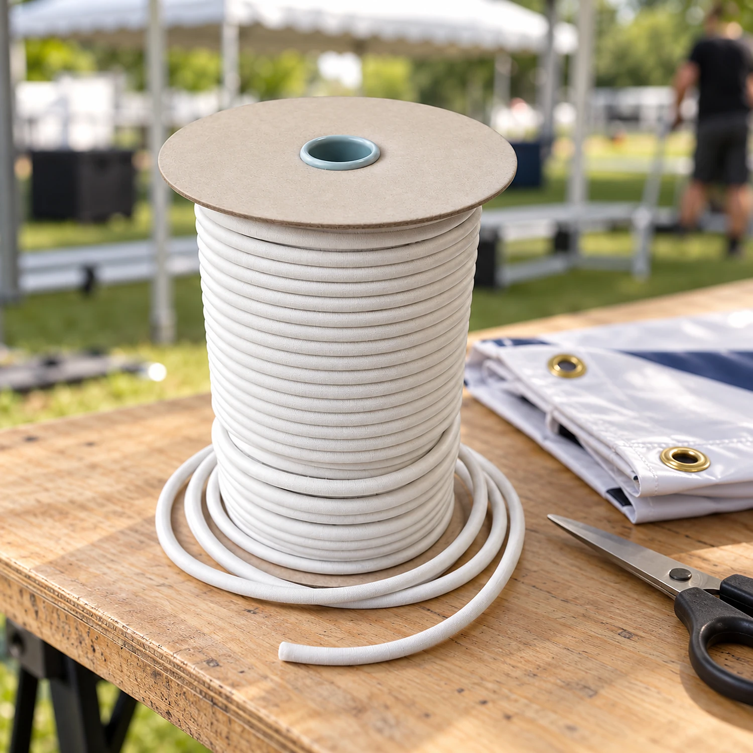 Spool of white bungee cord beside scissors and a folded banner