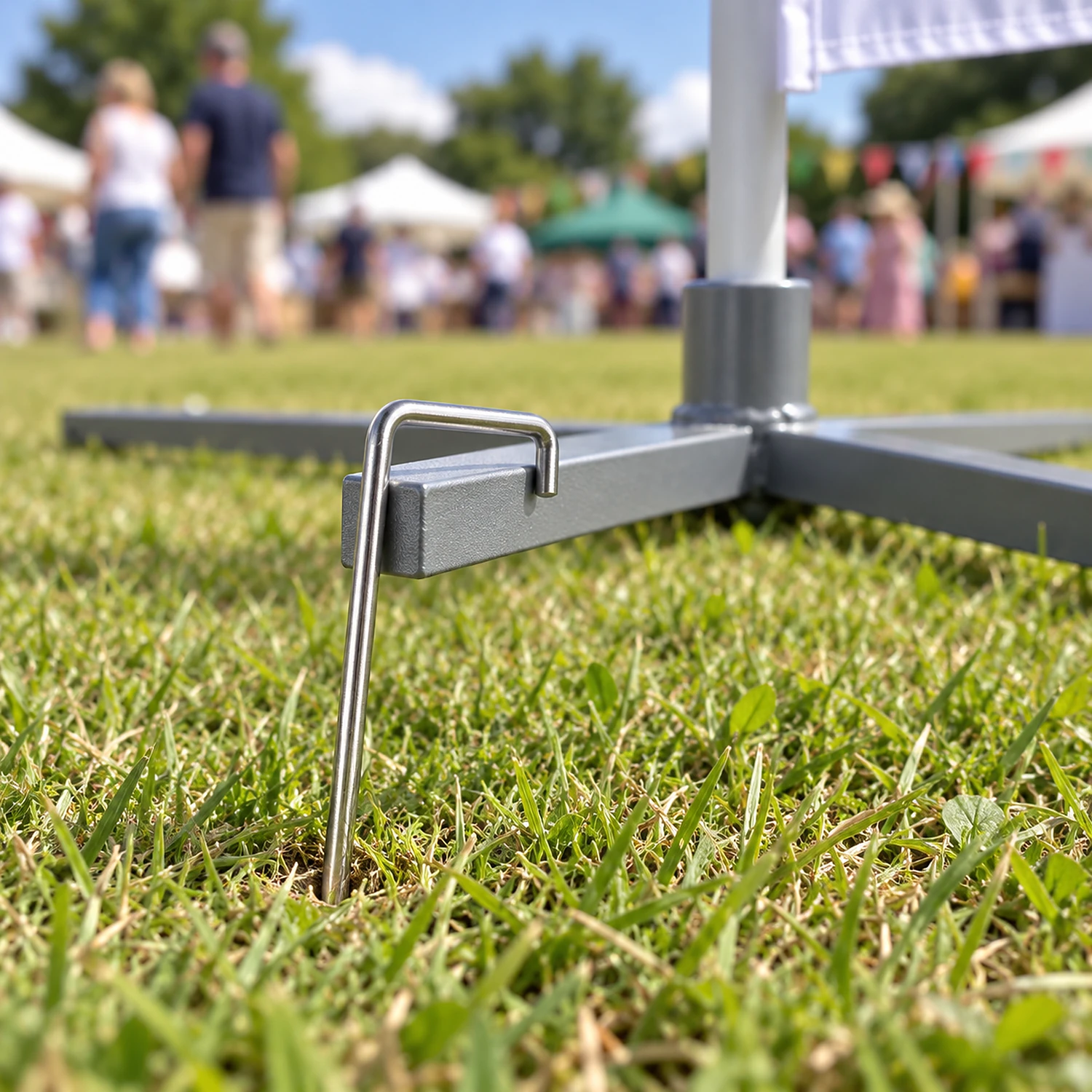 Hooked ground peg pinning a cross base arm on a lawn