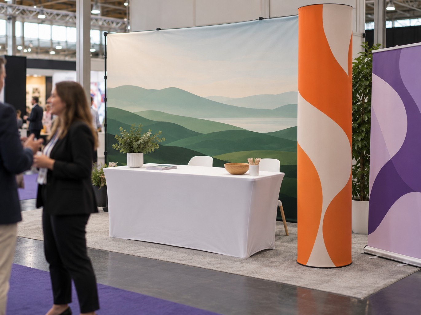 Exhibition stand with a wide fabric backdrop behind a table, a fabric totem and a roller banner at the front